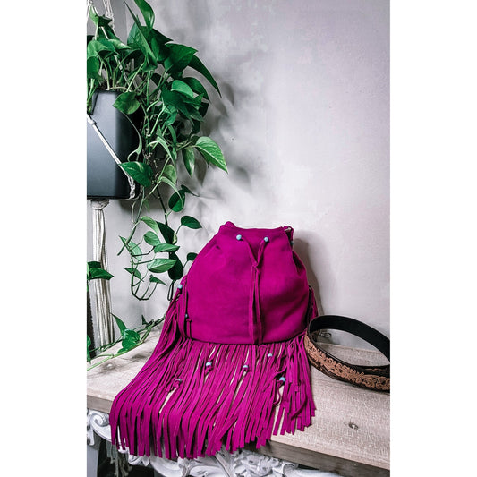 Bold and Beautiful fuchsia suede western fringe bag with turquoise bead accents and tooled adjustable strap that is a custom add on shown on wooden shelf