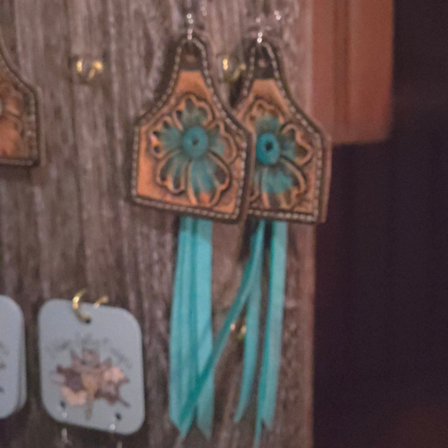 Tooled leather western-style earrings with turquoise floral detailing and long turquoise leather fringe