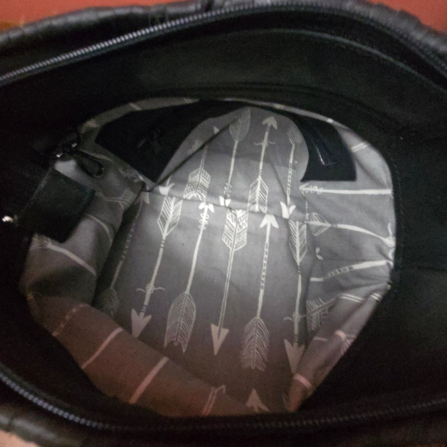 The inside of a black bag showing a gray and white patterned lining with vertical arrows.