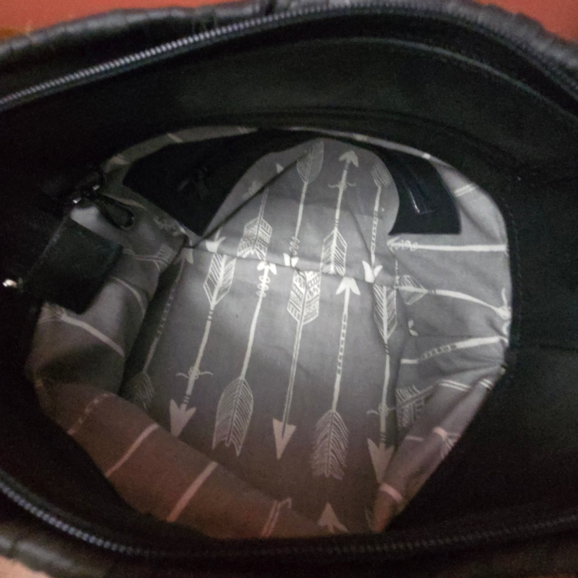 The inside of a black bag showing a gray and white patterned lining with vertical arrows.