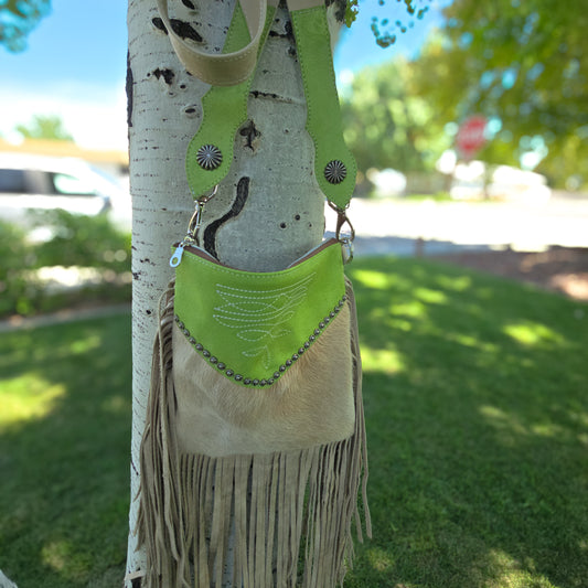 Margarita lime green suede hair-on-hide crossbody bag with fringe hanging in tree