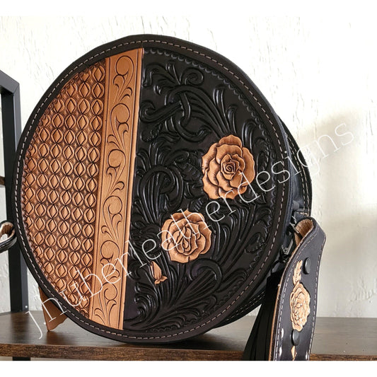 Midnight Rose hand-tooled western leather round bag with rose scroll tooling and black suede back angled front view on wood shelf