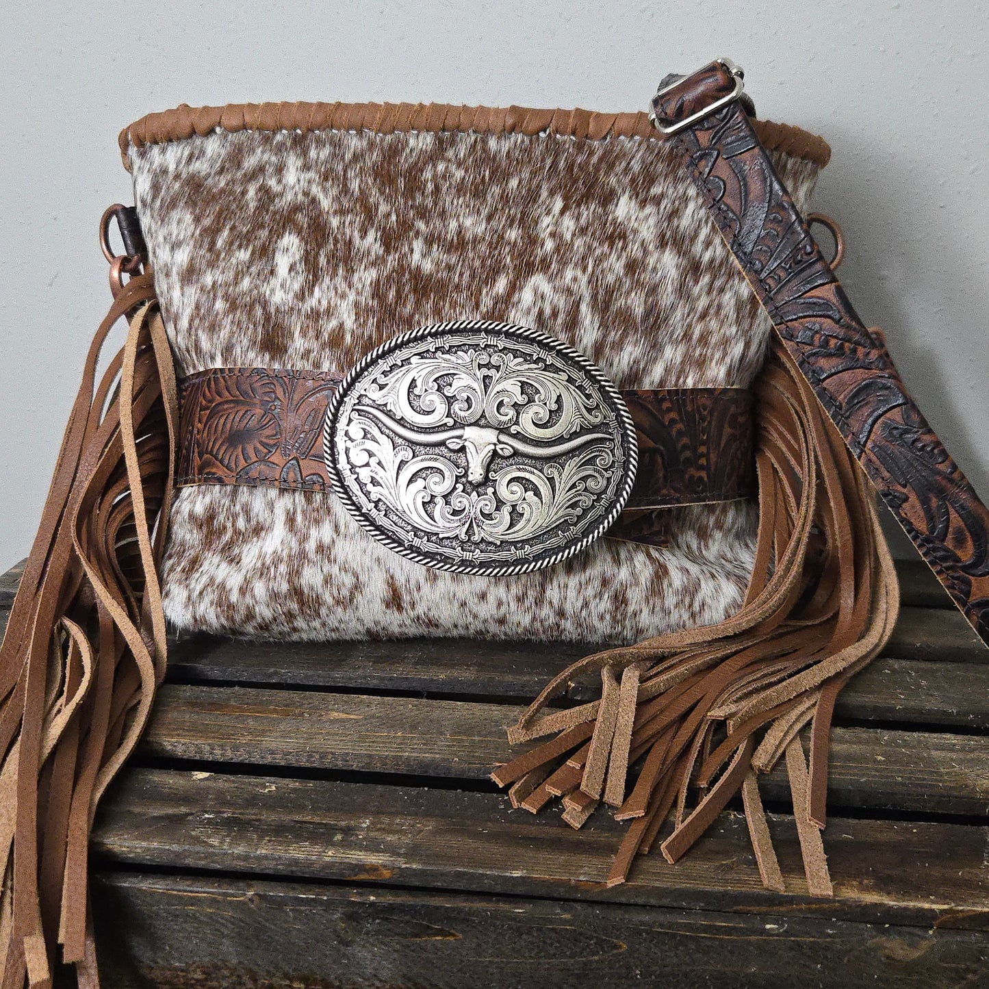 Small Buckle Bag with speckled hair-on-hide front, trophy buckle feature, embossed strap, and fringe