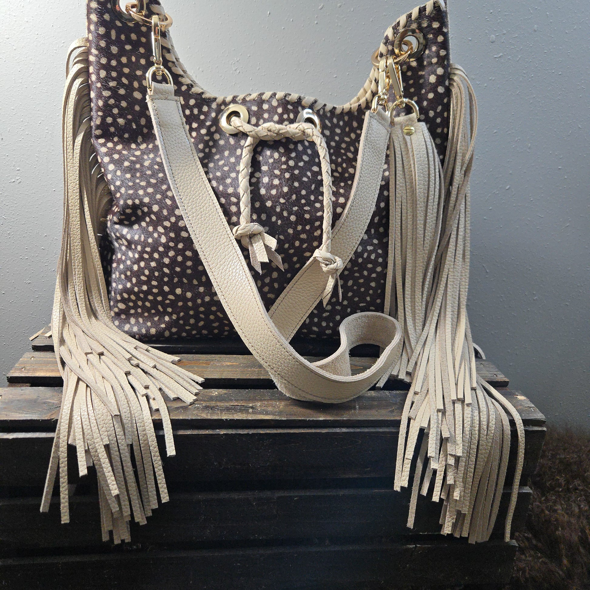 Uptown Cowgirl brown and cream hair-on-hide fringe bag with spotted hide front, cream leather strap, and side fringe