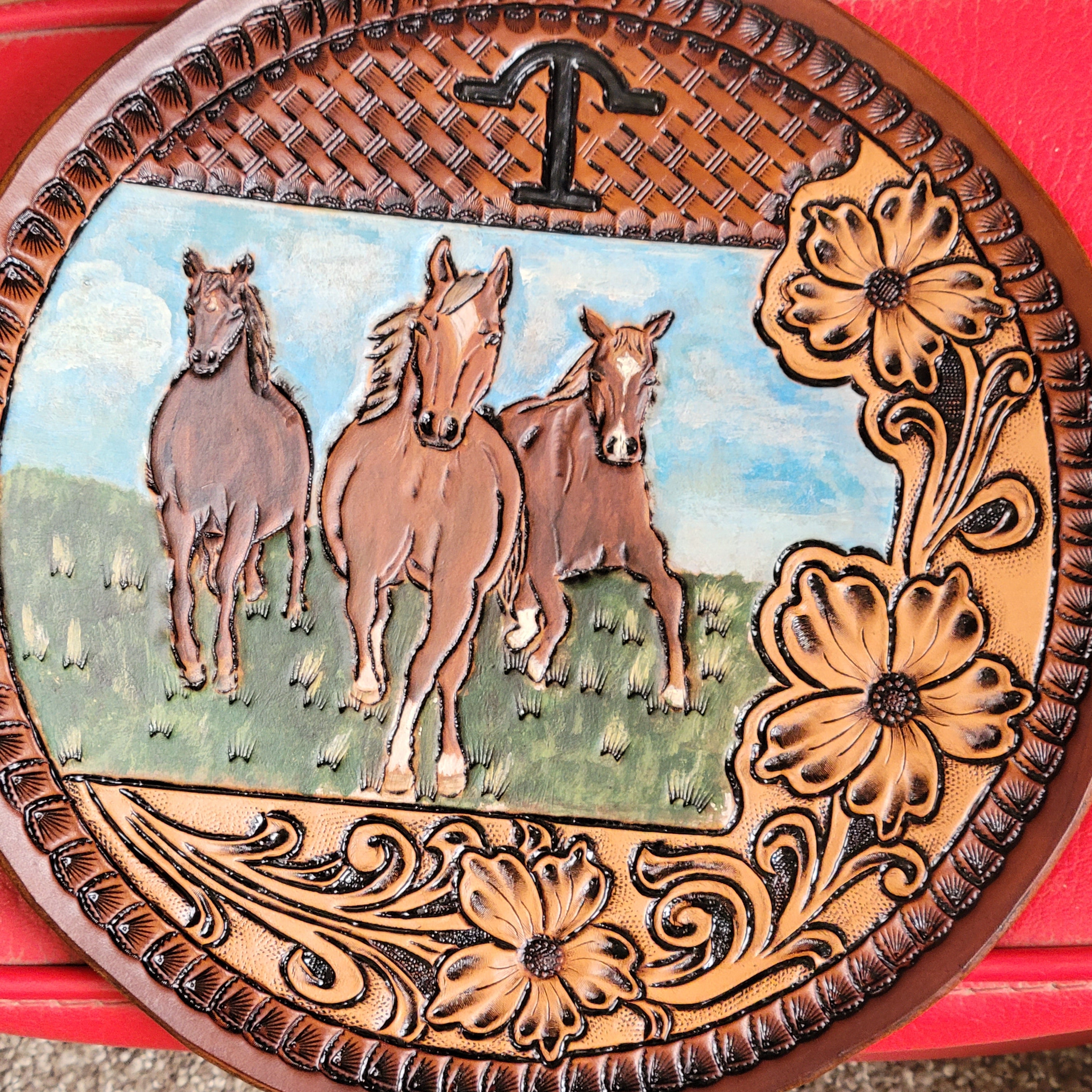 tooled leather round bag close up sitting on red leather ottamon